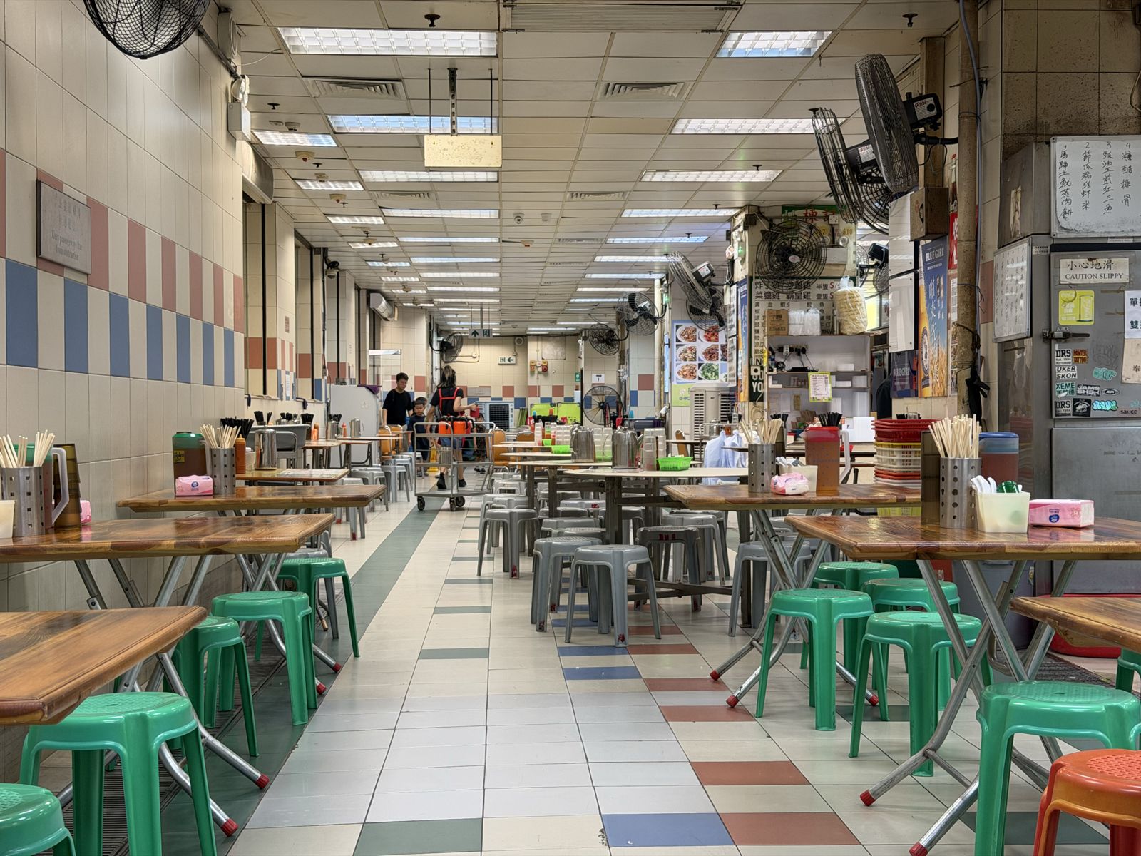 An empty cooked food centre with green stools
